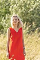 une jeune femme blonde vêtue d'une robe brillante se tient au milieu du terrain, les bras tendus. bonheur, liberté, été, vacances photo