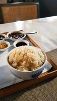 gros plan de riz huileux avec une sauce sucrée, épicée et salée floue pour manger avec du poulet bouilli à la thaïlandaise ou à singapour sur un plateau en bois sur la table. concept de cuisine asiatique. photo