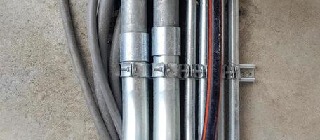 pipeline en acier inoxydable, en caoutchouc gris ou gris installé sur fond de mur ou de sol avec espace de copie dans l'industrie. le tuyau protège le fil électrique et de communication à l'intérieur et transporte le gaz ou l'eau. photo