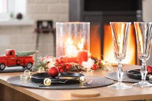 l'intérieur festif de la maison est décoré pour noël et le nouvel an dans un style loft avec poêle noir, cheminée, arbre de noël. chambre studio chaleureuse avec table dressée, feu de bois, cosy et chauffage d'accueil photo