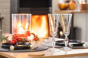 l'intérieur festif de la maison est décoré pour noël et le nouvel an dans un style loft avec poêle noir, cheminée, arbre de noël. chambre studio chaleureuse avec table dressée, feu de bois, cosy et chauffage d'accueil photo