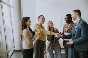 les membres de l'équipe créative se serrent la main tout en travaillant dans le bureau moderne photo