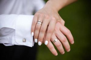 mains de la mariée et du marié avec des anneaux. mariés dans un café. table de bouquet de mariage. la mariée et le marié se tiennent par la main. anneaux de mariage. couple d'amoureux dans un café. thé chaud pour les amoureux photo