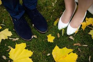 pieds de la mariée et du marié. la mariée et le marié se tenant la main et marchant sur la route dans la nature. en plein air. vue vers le bas sur les chaussures. photo