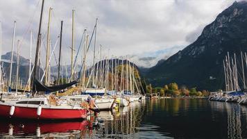 amarrage de yachts à voile sur un lac de montagne contre des silhouettes de montagnes et des nuages, vue sur la marina avec des voiliers colorés, paysage d'automne photo