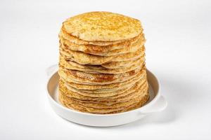 une pile de crêpes fraîchement cuites se trouve sous forme de céramique blanche. photo