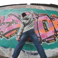 un jeune homme dans un sweat à capuche gris peint des graffitis en rose et vert c photo