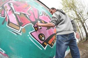 un jeune homme dans un sweat à capuche gris peint des graffitis en rose et vert c photo