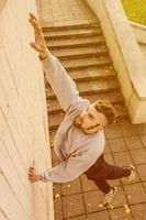 un jeune homme surmonte des obstacles, grimpant sur des murs en béton. l'athlète pratique le parkour, s'entraînant dans des conditions de rue. le concept de sous-cultures sportives chez les jeunes photo