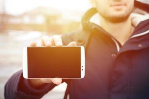 un jeune homme montre un écran de smartphone en arrière-plan photo