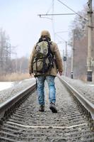 un homme avec un grand sac à dos va de l'avant sur la voie ferrée duri photo