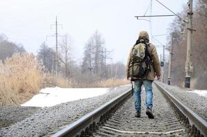 un homme avec un grand sac à dos va de l'avant sur la voie ferrée duri photo