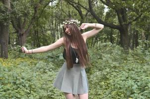 une photo de forêt d'une belle jeune brune d'apparence européenne aux yeux marron foncé et aux grandes lèvres. sur la tête de la jeune fille porte une couronne de fleurs, sur son front des décorations brillantes