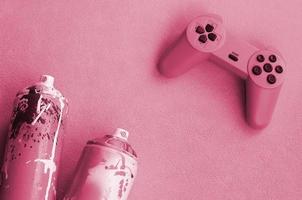 concept de mode de vie des adolescents et des jeunes. le joystick et deux bombes aérosols se trouvent sur l'image de la couverture dans les tons de magenta viva, couleur de l'année 2023 photo