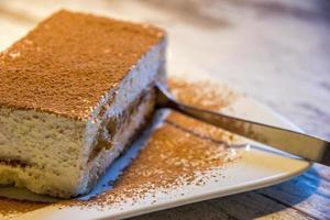 gâteau tiramisu dans une assiette blanche sur la table avec une cuillère. photo