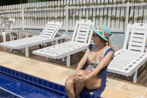 femme portant un maillot de bain une pièce et une couverture bleue au bord de la piscine photo