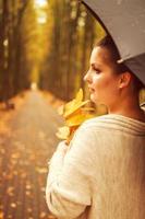 femme avec un parapluie se promène dans le parc d'automne photo