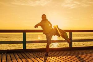 papa et fils jouant sur la jetée sur la mer au coucher du soleil photo