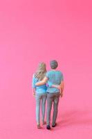 personnes miniatures homme et femme en tissu décontracté debout ensemble sur fond rose photo