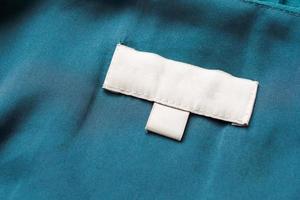 étiquette blanche de vêtements de soin de blanchisserie vierge sur fond de tissu photo