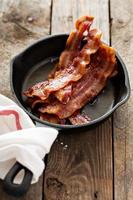 bacon chaud grésillant dans une poêle en fonte photo