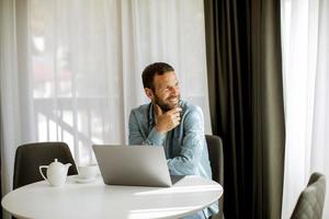 jeune homme utilisant un ordinateur portable et buvant du thé dans le salon photo