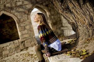 jeune femme assise sur le banc regardant l'arbre à feuilles jaunes dans le parc d'automne photo