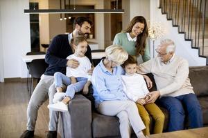 famille multigénérationnelle assise ensemble sur le canapé à la maison et regardant la télévision photo