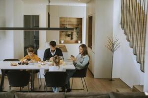 famille utilisant des téléphones portables tout en prenant son petit déjeuner à la table à manger de l'appartement photo