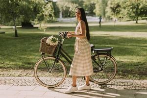 jeune femme avec des fleurs dans le panier de vélo électrique photo