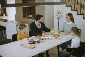 jeune famille heureuse parlant tout en prenant son petit déjeuner à table à manger photo