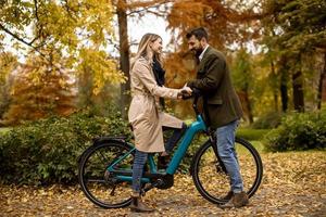 jeune couple dans le parc d'automne avec vélo électrique photo