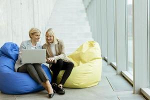 femmes d'affaires utilisant un ordinateur portable sur des sacs paresseux dans le bureau moderne photo