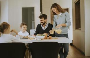 jeune famille heureuse parlant tout en prenant son petit déjeuner à table à manger photo