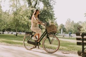 jeune femme faisant du vélo électrique avec des fleurs dans le panier photo