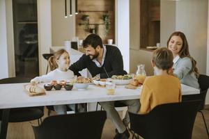 jeune famille heureuse parlant tout en déjeunant à table à manger photo