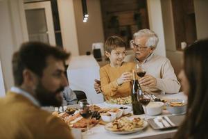 famille heureuse en train de dîner avec du vin rouge à la maison photo