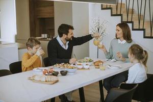 jeune famille heureuse parlant tout en prenant son petit déjeuner à table à manger photo