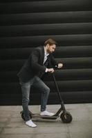 jeune homme d'affaires utilisant un téléphone portable sur un scooter électrique photo