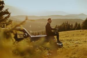 jeune homme se reposant sur un capot de véhicule tout-terrain à la campagne photo