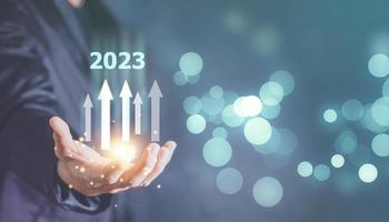 nouveaux objectifs, plans et visions pour l'année prochaine 2023. un homme d'affaires dessine une augmentation du graphique en flèche de la croissance future de l'entreprise de 2022 à 2023. planification, opportunité, défi et entreprise photo