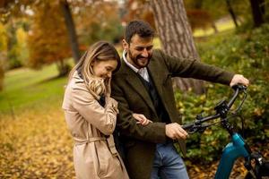 jeune couple dans le parc d'automne avec vélo électrique photo