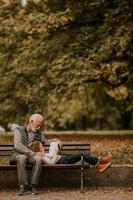 grand-père passe du temps avec sa petite-fille sur un banc dans le parc le jour de l'automne photo