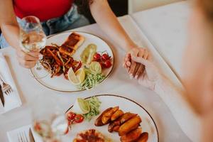 jeune couple en train de déjeuner avec du vin blanc au restaurant photo