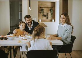 jeune famille heureuse parlant tout en déjeunant à table à manger photo