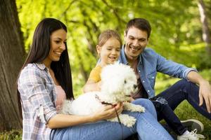 belle famille heureuse s'amuse avec un chien bichon à l'extérieur photo