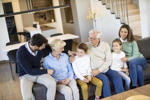 famille multigénérationnelle assise ensemble sur le canapé à la maison et regardant la télévision photo