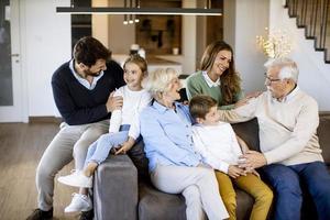 famille multigénérationnelle assise ensemble sur le canapé à la maison et regardant la télévision photo