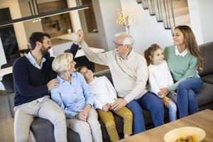 famille multigénérationnelle assise ensemble sur le canapé à la maison et regardant la télévision photo