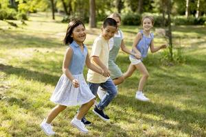 groupe d'enfants asiatiques et caucasiens s'amusant dans le parc photo